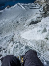 At 6,100m we reached the summit ridge. Each looked over the lip and along the very steep and exposed traverse across hard ice to the summit, a further ninety metres up. As the bitter wind whipped the fixed line Kami said a little anxiously “Route no good today.” There was no argument on my part – Kami had climbed Imja Tse fourteen times already; and my tolerance for suffering had reached its limit. Before we commenced our retreat I took some photos. It was 8.15am.
This picture, looking back down the headwall from the summit ridge.