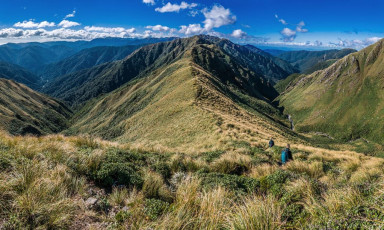 With such changeable weather, I wanted to be on the trail first thing on the Sunday so we could hopefully enjoy clear weather between Bridge Peak and Maungahuka Hut. In the car park, just before 8am, I chatted briefly to a guy who was looking after a group of kids on a geological trip. He mentioned that a party of trampers had taken over ten hours to get out from Waitewaewae Hut the day before, due to a slip somewhere along the route. Hmm, last time I came that way it had taken four hours. I hoped we weren’t going to endure a sting in the tail this time. “But it’ll be what it’ll be. Right now it’s time to climb.” This image - On the descent from Bridge Peak on to the main Tararua Range, looking north east, with Hector River right and Penn Creek left