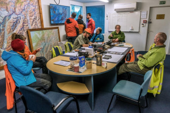 Soon reunited with our key and, after demolishing Pip’s heavenly chicken soup and other treats, we drove into Mount Cook Village to debrief with the SAR team. Along with Jono, Ray Bellringer (Incident Management Coordinator), Lee MacIntosh, Lewis Ainsworth and Madonna Fraser were all there to talk with us over cups of tea and biscuits. While we hadn’t activated our PLB and were able to get out under our own steam, DOC had raised the alarm based on knowing we were overdue and that the weather conditions were dangerously bad. We felt immensely grateful to the dedicated team for all their efforts on our behalf; and reassured to see firsthand how alert and responsive our SAR people are.
The SAR team did not scold us. They just wanted to understand fully all the facts. We on the other hand did some soul searching over the next couple of days and concluded that we did make some mistakes. The main one was to underestimate the difficulty of moraine travel, especially when we knew we faced deteriorating weather. This alone meant we left Plateau Hut later than we could have and we didn’t carry a cooker or full camping gear. Our focus was mostly on safely passing crevassed terrain, which proved to be much less challenging than being on steep scree and moraine in dark, wet conditions. Our price was to endure the longest night of our lives. And it could have been much worse.
This image - At the SAR debriefing. While we hadn't needed rescuing, given the weather and terrain, we could have. We greatly appreciated the efforts that the SAR team made on our behalf.