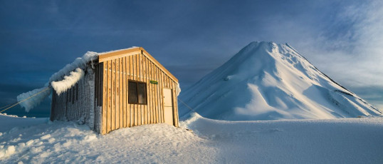A gem it is, but a cold one. In such a spot there is no fuel for a wood burner. I’ve been at Syme before when the entire hut was thickly encased in rime ice – so much so that I cramponed up one of the outrageously ice encrusted weather stabiliser cables on to the roof. That time we had to make a considered guess about where the door was and start hacking with our axes. This time the hut was only partially coated. It still had its magnificent, ghostly west-end formations in place, but the east facing split door was mostly clear. We climbed in via the free swinging top half of the door and later, with a bit of toil, I was able to free the bottom half of hard ice, permitting normal entry and exit.