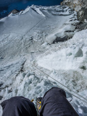 At 6,100m we reached the summit ridge. Each looked over the lip and along the very steep and exposed traverse across hard ice to the summit, a further ninety metres up. As the bitter wind whipped the fixed line Kami said a little anxiously “Route no good today.” There was no argument on my part – Kami had climbed Imja Tse fourteen times already; and my tolerance for suffering had reached its limit. Before we commenced our retreat I took some photos. It was 8.15am.
This picture, looking back down the headwall from the summit ridge.