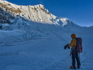 With virtually no sleep, it was adrenalin and ambition that got me up and away into the sub-zero darkness. As we climbed in the glow of our headlamps the biting wind intensified. We zigzagged up through bluffs for about 800 metres before reaching the base of the ice. It was colder than I had experienced ever before and unfortunately, it was still an hour away from dawn. We didn’t want to venture up into the icefall until we had some visibility, but despite double gloves, while we waited my hands were quickly freezing. All I could do was slap my hands against my thighs and jog on the spot, performing a demented form of high altitude haka – for 45 minutes nonstop, to keep semi warm. This picture, at the base of the 200m headwall, with the summit.