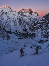 Skiers below Homer Saddle at dusk. Mts Crosscut and Christina behind.