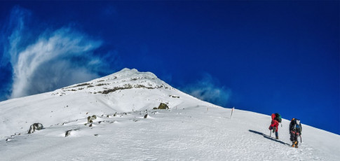 I’ve been up this standard route twice before in winter but, due to the thin conditions this time, the poles were much more prominent. Swirling cirrus fingers reaching out over the summit suggested that a nice easy-to-follow handrail on the descent would be reassuring. I assumed, wrongly as we soon discovered, that the poles marked the route I’d been up before over easy terrain into the summit crater. So off we went, smashing off ever larger rime chunks as we went, so the orange tipped poles were easier to spot on our descent.