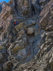 As I passed the steep section beneath the summit chute and saw it from a new perspective I suddenly saw a possible way up and said so. Youthful exurberance kicked in. “I’ll give it a go” and Mike made a beeline to the base of the chute. “Shite, now I’ve done it!”
Mike did well, methodically picking his way up, reaching a safe spot to stop so I could follow without having any lose rock topple onto me. Another very airy little move just below the summit on untrustworthy rock saw us on top at about 2pm. And our fear was realised – a very exposed, sheer notch lay between us and the true summit a few metres above us – we couldn’t go forward.