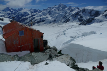 As good as it gets – Tasman Saddle Hut.  We had arrived in zero viz in the morning, having thrillingly arrived in the Cook District over a nearly-impassable Tasman Saddle that morning.  We had planned to be here on a fining forecast at least three days, and maybe 20 hours of travel, prior.  The next day we would climb Elie de Beaumont, New Zealand’s fifth highest peak, in very trying condition over 17 hours.  Getting up every mountain needs time, weather, conditions, friends, and maybe funds.  Positioning ourselves was a significant extra challenge on the Traverse.  Views over both coasts and a good deal of one’s memories make it worth the effort.