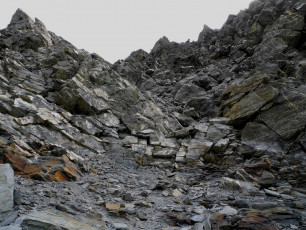 Back down at the Col Steve elected to be rude so, alone, I began my scramble up scree towards some small, crumbling cliffs. Expecting just a slog up scree I’d left my crampons, axe, harness and rope behind with Steve. As I climbed the cliff though, I started to wonder if that had been a mistake. Climbing the crumbling rock was okay but, knowing that descending can be more difficult than ascending a given route, I was feeling less and less keen to retrace my steps on this one. I consoled myself that I’d seen some other potential escape routes on the approach, so put the descent to the back of my mind.