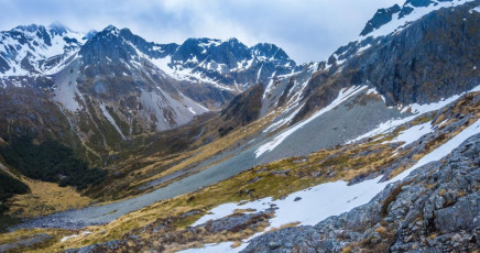Soon we pitched, more for practise than necessity, a rope length down a snow chute on to a broad snow field one further over from the one we’d ascended that morning. It was then just a plod back around the 1600m contour until Upper Traverse Hut came into view. Back in the Hut about 3.30pm Travers’ summit was shrouded in swirling cloud and the first rain drops began to fall. It’s always disappointing not to reach the top, but at least this made us feel like we’d made the right call to bail when we did. This image - On the traverse around at about 1,600m, with Upper Travers Hut bottom left.