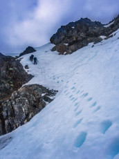 At 1,900m we paused beneath a rock buttress on the lip of a tiny schrund to rearrange gear and discuss our next move. Simon lead up through steep snow around patches of rock while I waited a bit to get some photos. By the time I caught them up we were all starting to feel the early emotional impacts of sustained and increasing exposure. I led on through and decided to test my theory about the rock looking friendlier than the snow at that point.