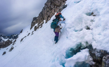 The snow was a problem – while the steps we kicked as we pot-holed upwards were deep, they sometimes gave way without warning. Our route took us up steep, exposed snow slopes, interspersed with stretches of shattered rock. Our ropes remained in the pack because there were no possibilities to put in solid protection. Our axes were really only good to aid balance – successful self arrest was very unlikely. This image - Departing the lip of a small schrund in the direction of the ridge, about 1,900m.