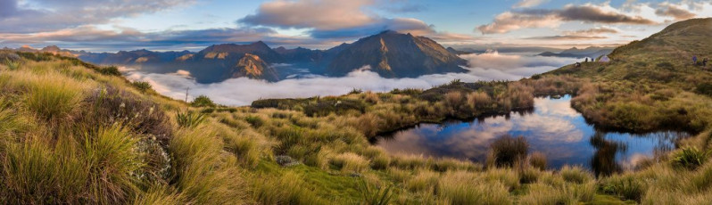 If we’d followed the original plan we’d have missed all this tops action because, as day four wore on, the weather slowly began to deteriorate. As it was this wasn’t a problem because, once we dropped steeply off Biggs Tops to Trevor Carter Hut (500m), the next two days were all in the forest, tracing the Karamea River.
This image - Looking across the tarn to the Scarlett Range (left), Mt Herbert and Mt Kendall (right).