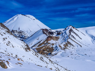 Descent from our lunchtime high point saw us also back to the main route, which we would follow southward back to our cars. As we cramponed along, we met a couple of young guys in sandshoes, parkas and not much else. Granted, the conditions were perfect, but the irresponsible idiocy of their clothing had me shaking my head. Ignorance? Arrogance? Disrespect? Or a combination of all three!
Even on a trail bereft of snow due to the heavy traffic it receives, it was still a 200 metre vertical slog up to the top of Red Crater’s rim from the southern edge of Central Crater. Unlike in summer, when the two little Emerald Lakes can’t be missed on this section of the trail, they were frozen and nowhere to be seen. Even so, each high point rewarded us with yet another magnificent panoramic perspective of the otherworldly volcanic landscape. After all, the Tongariro Crossing is famous for good reason. Our own tour of the Tongariro craters had certainly been memorable. This image - Red Crater and Ngauruhoe.