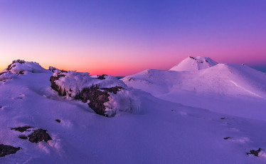 Eventually the first hint of dawn arrived and I extracted myself, somewhat stiffly, from my cocoon. From our camp we had the view point options of Tongariro’s summit (1,967m) or the slightly lower rim (1,909m) of North Crater. Having been up Tongariro several times I chose the latter. It was a relief to feel the warmth of uphill movement as I made a beeline for North Crater’s outer rim 100 metres above. My crampon spikes squeaked as they bit effortlessly into the firm snow. At last, for the first time this winter, I was blessed with perfect alpine conditions. This image -Dawn on North Crater's southern rim (1,909m). Tongariro's (1,967m) and Ngauruhoe's (2,287m) summits behind.