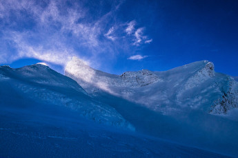 As we plugged down the glacier the effect of the bright winter sun was evident. The firm conditions of the morning had gone. Now we had to be mindful of avalanche risk as we passed the convex snow bulge on the upper glacier. About 4pm we again reached the ski field, closing our day’s loop. This image - A lightshow unfolds in the early afternoon, as spindrift and the steep south face of Tukino catch the sun. Te HeuHeu is far right.