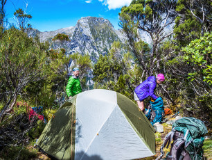 From the Footstool was a 150m steep descent to a saddle where we encountered the first of two small campsites. At the first was a pan, half filled with rain water – an unexpected bonus given the lack of water sources on Mitre Peak. A little further on, at 730m, was the second campsite where we decided to stay. Later Simon discovered a nearly dried out tarn nearby, where he scrounged a couple of extra murky litres of water which we thoroughly boiled for tea. Water is an issue. In such tough terrain you need plenty, but you have to carry it, which makes pack lugging more arduous.
We also carried a 60m rope, harnesses and a few slings. Depending on who you talk to Mitre Peak is touted as a straight forward rock scramble through to a truly epic undertaking. We took the gear just in case, but that only added more weight to our packs. As it turned out for us, the truth was somewhere in between. If we’d had more time I’m certain we would have free climbed the entire route and my background is not a rock climber. But unless you’re an Alex Honnold kind of guy, the yawning exposure can’t be ignored. Climbing up or down the upper sections of Mitre Peak is a mind game to some degree. I was acutely conscious much of the time that a single misplaced step or careless hand hold would end in a freefall to the fiord.
This image - Our camp at 730m.