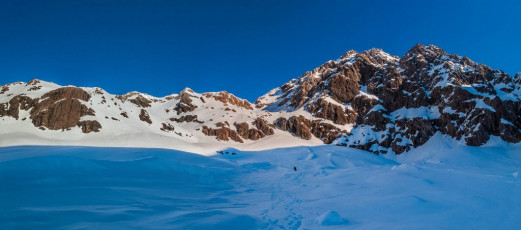 Although steps led off along Goldney Ridge, we decided to drop off down the Slide almost immediately after reaching the ridge. Being wary of afternoon avalanche danger, we kept close to the edge of the snow slope until it broadened out and the gradient relented at about 1,600 metres. “This takes me back three years James” I remarked as we crashed thigh deep into soft wet snow. While there was still some gradient to work with the best way forward was on our bums. Thankfully the snow improved a bit once we reached the shade of the Philistine Ridge and then it ran out altogether at about 1,200 metres.
This image - Below Otira Slide at about 1,500m, with Mt Rolleston's northeast face above right.