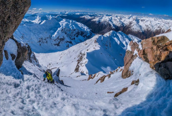 Our round trip from Low Peak to the summit and back had taken about two and half hours, so we set off on our descent to Goldney Ridge about 2pm. The going was steep, mostly facing in to the slope, but straight forward. By now any freeze had well and truly become a distant memory in the bright sunlight. Any thought of climbing it made me wince, but the snow was actually quite pleasant for descending – soft but predictable. Looking below at the Otira Valley I could see one or two avalanche sites, but generally everything appeared pretty stable – in line with the “moderate” rating given by avalanche.net.nz.
This image - On the descent at about 2,100m, with Goldney Ridge below centre.
