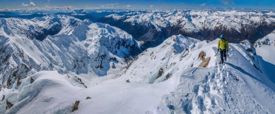 “It’s still sinking in that I’m actually on top James. I’ve been looking at this peak for three years. Life is good!” The summit of Mount Rolleston is just the 2,275 metre high point on a long narrow ridge. There wasn’t a huge amount of room up there and the wind was up so, after I’d covered, to my satisfaction, all angles photographically, I carefully followed James back to our packs back at my T slot point. An easy pitch and a reassuring 30 metre abseil later saw us back down in the notch, comfortable in the knowledge that the rest of our day should be quite straight forward.
This image - Looking north and east from the summit, with Goldney Ridge centre, Otira Valley left of centre and Mt Philistine further left, above Rolleston Glacier.