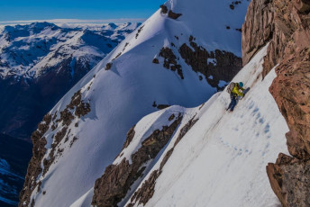 Just as I confirmed that down climbing was going to be fine, James also located a fixed sling up above me. We didn’t need it, but now we turned our attention to the next section, climbing out of the notch towards Low Peak – the crux. Steps again led both ways – left and right. “Which way James?” “Last time we definitely went right.” And off he went. As we struggled up through some exposed downward sloping, snow splattered rock, then a precarious little ice cheval, the advice the Arthurs Pass Oracle Graeme Kates had given me the evening before came flooding back. “My mate mentioned an unpleasant patchy rock and snow section just on the Bealey side of the ridge. Sounds like that is best to avoid if you can.” “Yes, I see what you mean now Graeme” I thought to myself as we carefully plugged up a steep, exposed snow face back on to the crest of the ridge – where, at 1,950 metres all the other steps reappeared.
This image - James making his way across a steep traverse on the Bealey side of the ridge.