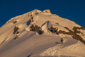 Alpenglow revealed a line of well-trodden steps stretching in to the distance up Rome Ridge. Weekend climbers had reported very soft, arduous snow, demanding too much time to get beyond Low Peak. But the weather had been settled now for four or more days and their still well formed steps provided us a staircase. The windless sky gradually brightened clear. Perfect! 
This image - At about 1,550m on Rome Ridge.