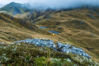 At one point a packless wrecky was needed to navigate seemingly bottomless bluffs, but after three or so hours we descended below the cloud base and saw beneath us a tiny yellowish orange box sitting beside a tarn. Brass Monkey Biv – its location was as evocative as its name.