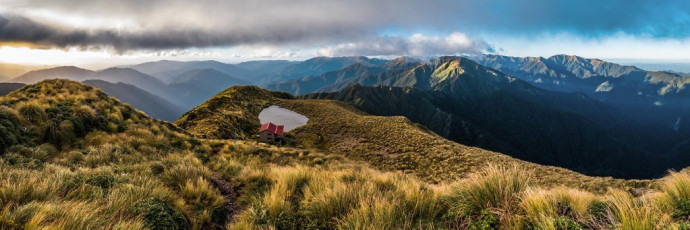 Twelve-bunk Maungahuka Hut, nestled into the tussock hillside beside a pretty tarn at 1,280m, deserves its reputation for being situated in one of the Tararua’s most spectacular spots. This became even more apparent, when I looked back from the ridge north of Anderson Memorial Hut the next afternoon, to see the main range unfold in clearing cloud. Right in the middle, at what appeared to be near the highest point, sat a tiny red dot commanding unimpeded views.