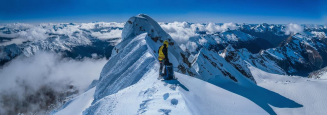 As thick clouds billowed up around us I felt a tinge of unease. It’s one thing being up on exposed terrain in good visibility but, in a whiteout, exhilaration quickly morphs into anxiety. Despite our 2,500 metre altitude, the snow was quite soft. Not predictable enough to trust to free climbing across the knife-edge. In fact, Piotr’s plan was to use my axe to build a T-slot anchor, so that he could use one of our two snow stakes to put in an interim anchor out on the knife-edge. As it was, an axe didn’t cut the mustard. We had to bury a snow stake about half a metre and compact the snow above it to build a half reasonable T-slot anchor, which I clipped in to as Piotr prepared to venture forth.