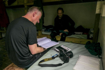 As the fire crackled and glowed, I reflected on what we’d read in the hut books during our journey. ‘More NOBOs. SOBOs. Heaps of them – at least between November and April. If we came back here in two months time we might struggle to get a seat beside the fire.’ Now that the Te Araroa Trail passes right along the Richmond Range it seems to have had a dramatic impact. Hut book entries painted a busy picture, even alluding to water shortages at times.  
This image - Shaun checking out the hut book at Old Man Hut (1,100m)